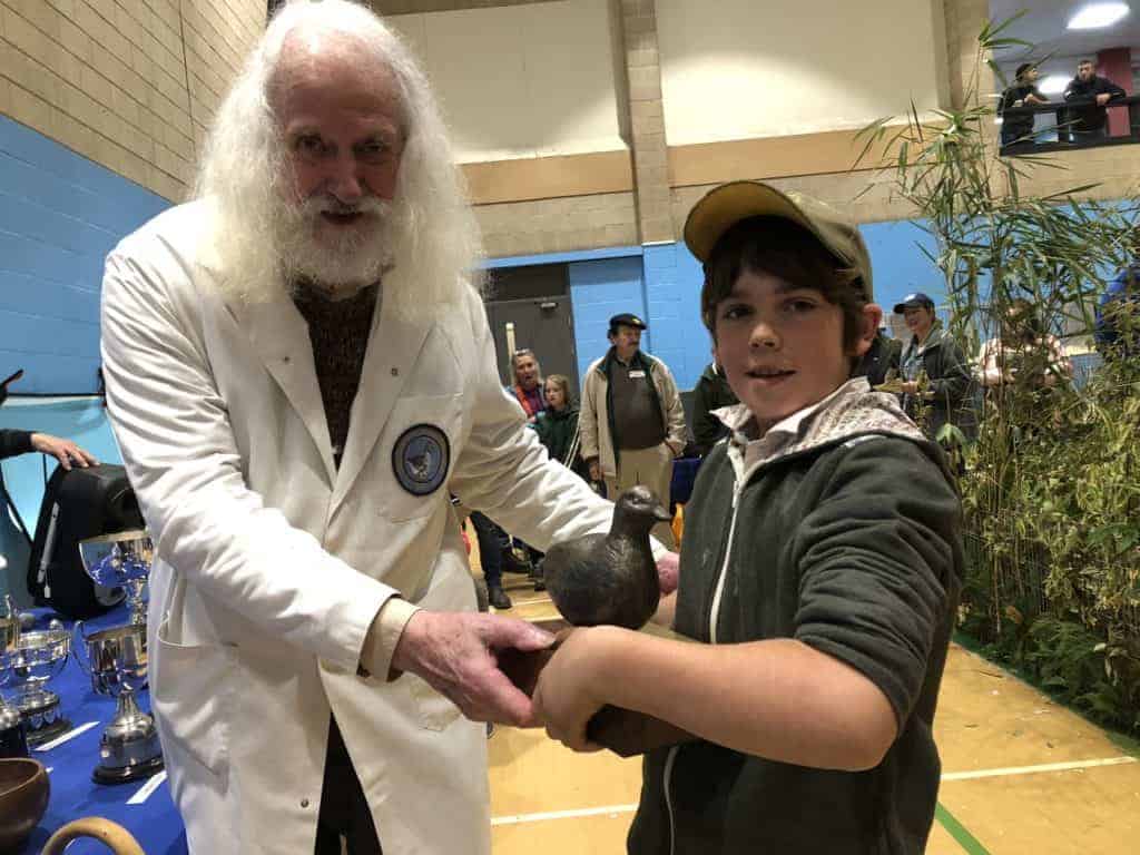 Young waterfowl exhibitor is handed a prize by an expert judge